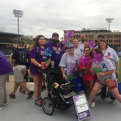 Group picture with team members and children outside a baseball stadium